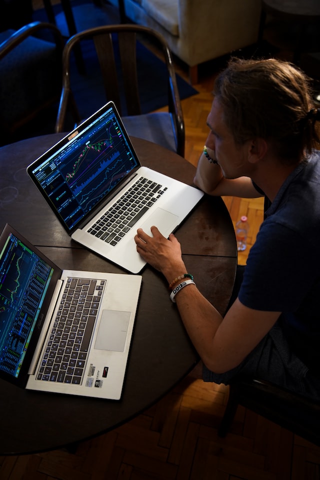 man working on data analytics using two laptops